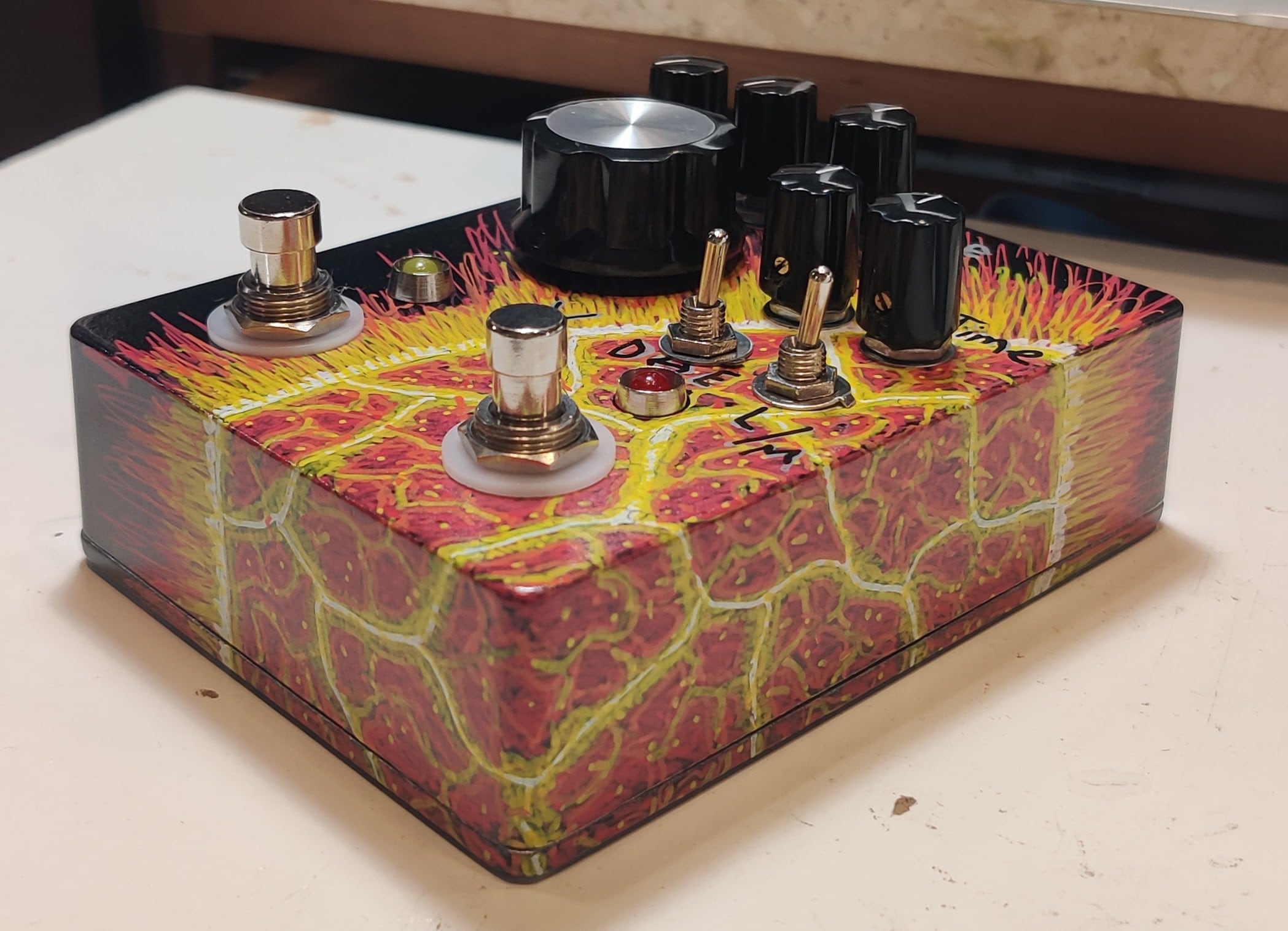 A black pedal with a hand-painted exploding sun seen from a low angle